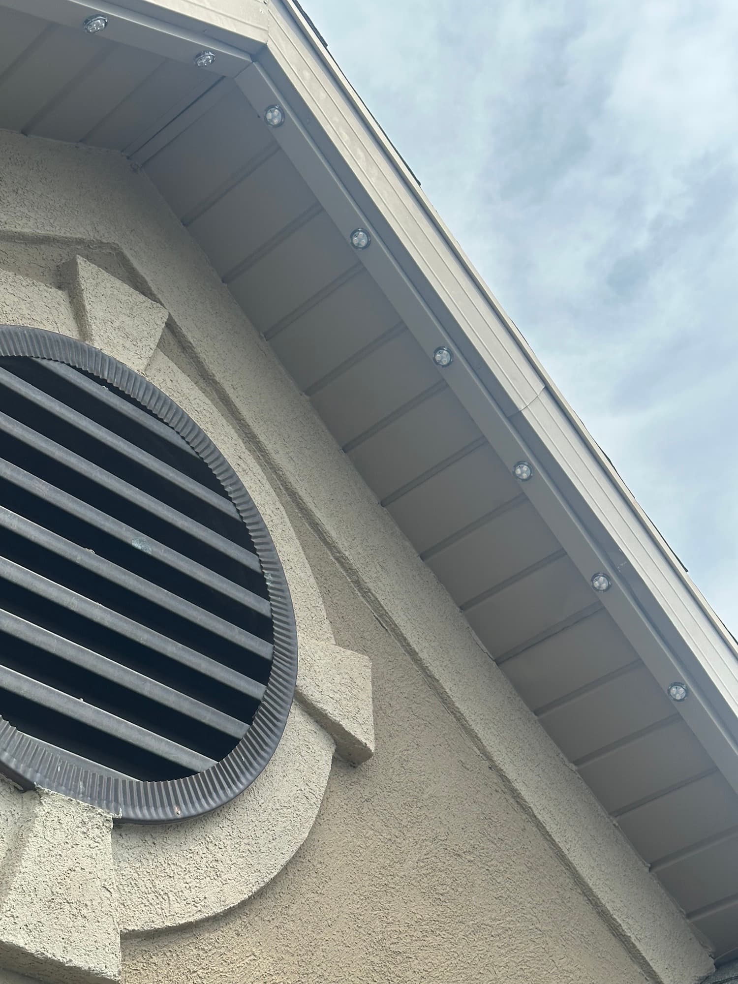 Close-up of a home's eave in daylight showing discreet permanent lighting fixtures that blend into the soffit